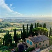 A photo of a field and house in Tuscany, one of the 2026 55+ World of Travel trips