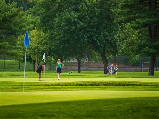 A photo on the golf course of two women playing golf and talking