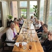 A table full of senior center members smiling while out at a restaurant