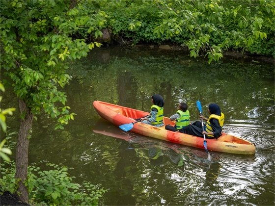 three people kayaking at creekside