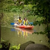 Two people in a kayak floating along Creekside
