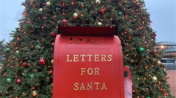 A large red mailbox titled "Letters to Santa" in front of a Christmas tree