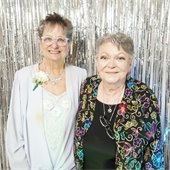 Two senior center members in front of a photo wall at senior prom