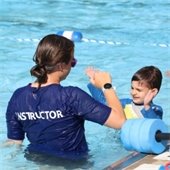 Child learning from swim instructor