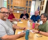four senior center members sitting at a table smiling with ice cream sandwiches