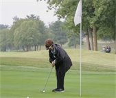 A woman on a golf course, preparing to hit the ball 