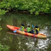 three people in a kayak, kayaking down a river
