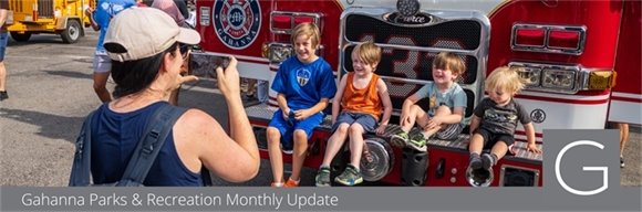 Four children having their photo taken while they sit on a firetruck during Touch a Truck
