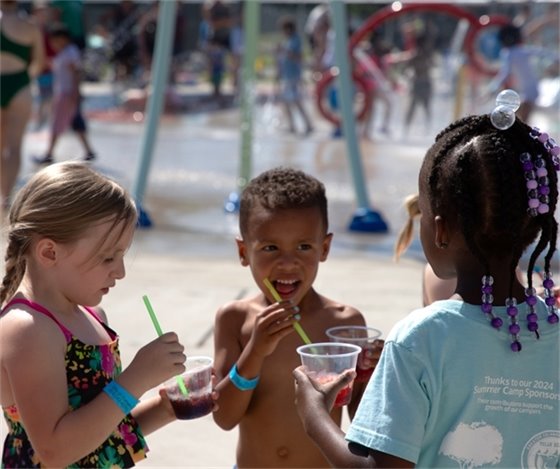 Three children together at the Splashpad enjoying snow cones