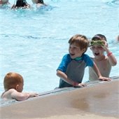 Three children smiling and playing in the pool together