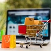 A tiny cart full of shopping bags and packages sitting in front of a laptop