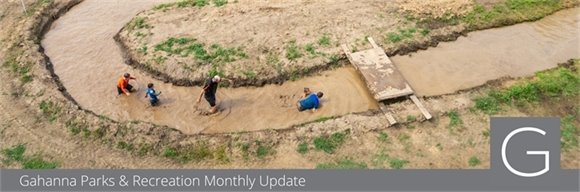 Drone image of participants running through a mud river at the Muddy Miler