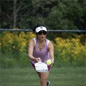 A woman playing pickleball wearing sunglasses and a visor