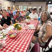 A group of senior center members smiling together at a table during lunch