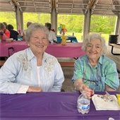 Two senior center members smiling at a table 