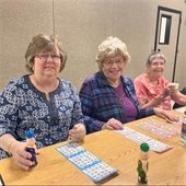 Three senior center members playing bingo together.