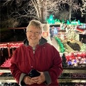 A Senior Center member smiling in front of a holiday light display