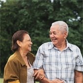 A senior couple with linked arms smiling at each other