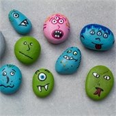 A few rocks on a table that have been painted with monster faces for Halloween