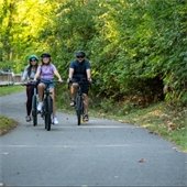 a family of three biking on a gahanna trail and smiling