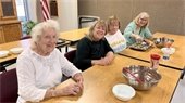 Four senior center members baking together at a table