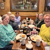 Senior center members sitting at a restaurant table together and smiling