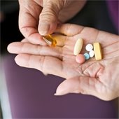 An elderly hand holding multiple medications