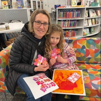 A mother and daughter holding up their craft after Storytime with Parks & Rec