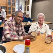 Two senior center members showing off their creations from a baking with lauren class