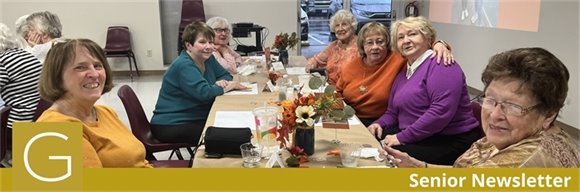 A table of senior center members enjoying a Thanksgiving meal together and smiling.