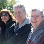 Three senior center members sitting together outside
