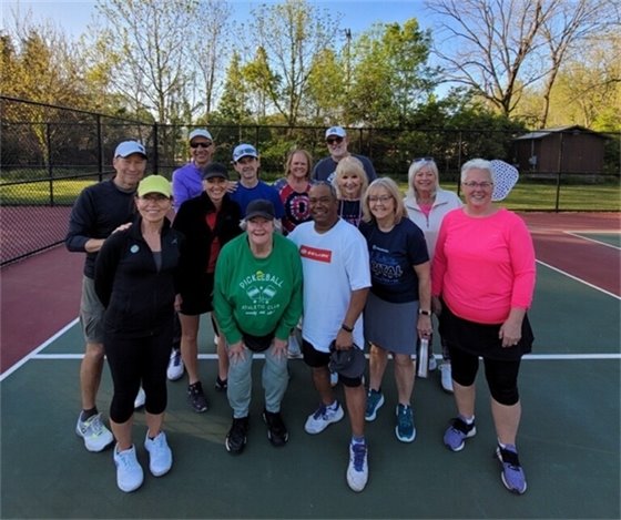 A group of adults standing on a pickleball field