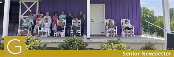 A group of senior center members sitting in front of a purple barn