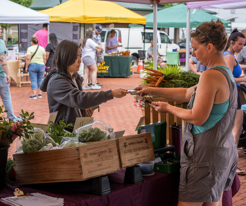 a woman buying produce from a farm stand at the Gahanna market